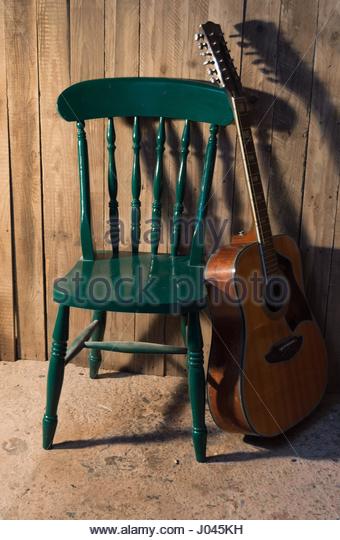 acoustic-guitar-against-green-wooden-chair-j045kh
